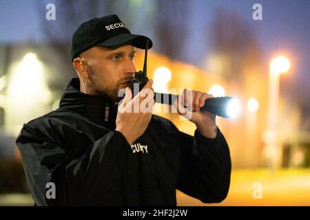 Security Guard Officer Using Walkie-Talkie Radio At Night Stock Photo