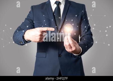 Businessman holding a lit light bulb. Concept of good idea, innovation, success or inspired mind Stock Photo