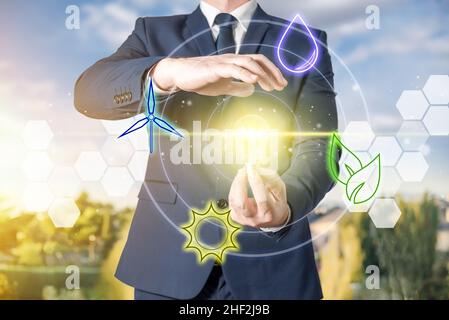 A businessman holds a light bulb lit by using renewable energy. Concept of environmental sustainability, ecology and energy saving Stock Photo
