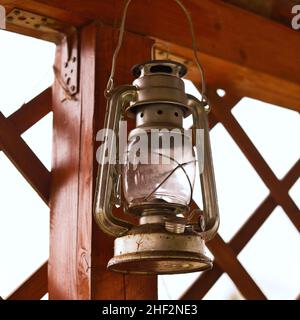 Vintage kerosene oil lantern lap hanging on wooden pillar. Old antique retro lamp. Stock Photo