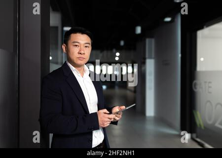Serious asian male worker focused on work working with tablet computer in modern office Stock Photo