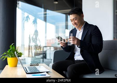 Happy asian businessman transferring credit card, happy and smiling man buying in online store sitting in office Stock Photo