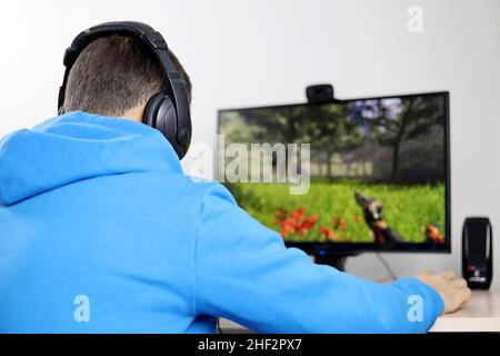 Guy in headphones playing a computer game on desktop PC. Concept of game addiction, home leisure Stock Photo