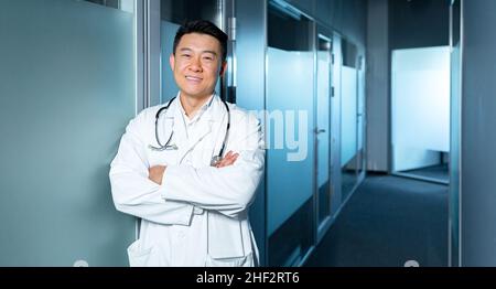 Portrait of a successful happy and cheerful Asian doctor, man in modern clinic looking at camera and smiling Stock Photo