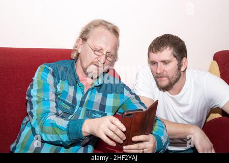 Two men are discussing the news while looking at the phone. Communication of friends. Stock Photo