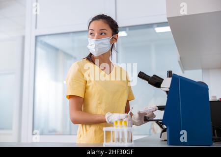 Woman vet examining samples and working with microscope in clinic Stock Photo