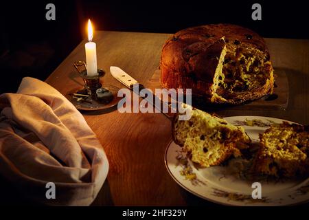 Panettone italian specialty Christmas cake with raisins and berries on a wooden table with burning candles Stock Photo