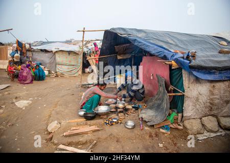 Ghaziabad, India. 13th Jan, 2022. A couple seen cooking food on a temporary arrangement outside a cluster slum in a derelict area.Poor people living in urban slum area of vasundhara, Urban poverty in India is now over 25 percent, close to 81 million people in urban areas live below the poverty line. Several reports indicate that the national level of around 150-199 additional million people will become poor due to COVID-19 crisis, while those who are already poor will be pushed deeper into poverty. (Photo by Pradeep Gaur/SOPA Images/Sipa USA) Credit: Sipa USA/Alamy Live News Stock Photo