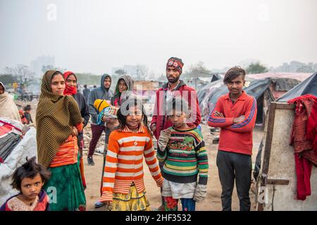 Ghaziabad, India. 13th Jan, 2022. Slum dwellers seen standing together with children amid cluster of slums.Poor people living in urban slum area of vasundhara, Urban poverty in India is now over 25 percent, close to 81 million people in urban areas live below the poverty line. Several reports indicate that the national level of around 150-199 additional million people will become poor due to COVID-19 crisis, while those who are already poor will be pushed deeper into poverty. (Photo by Pradeep Gaur/SOPA Images/Sipa USA) Credit: Sipa USA/Alamy Live News Stock Photo