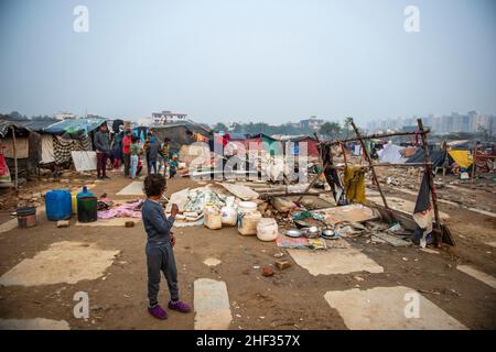 Ghaziabad, India. 13th Jan, 2022. A view of a derelict area inhabited by slum dwellers with their temporary arrangements and urban residences looming in background.Poor people living in urban slum area of vasundhara, Urban poverty in India is now over 25 percent, close to 81 million people in urban areas live below the poverty line. Several reports indicate that the national level of around 150-199 additional million people will become poor due to COVID-19 crisis, while those who are already poor will be pushed deeper into poverty. Credit: SOPA Images Limited/Alamy Live News Stock Photo