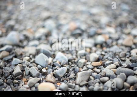 A background of wet pebbles, selective focus, back part out of focus. grey and brown tones. stones from the seashore. Stock Photo