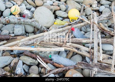 A rubbish among the rocks of the sea, plastic bottles, cans and fishermen's balls. Stock Photo