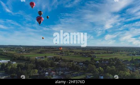 Aerial View of Many Hot Air Balloons Flying Across Rural Countryside During a Balloon Festival Stock Photo