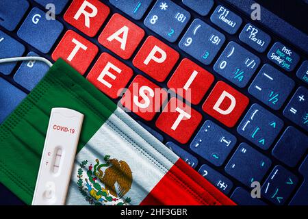 COVID-19 positive antigen rapid test kit on face mask with Mexican flag on computer keyboard. Concept of Covid testing in Mexico. Stock Photo