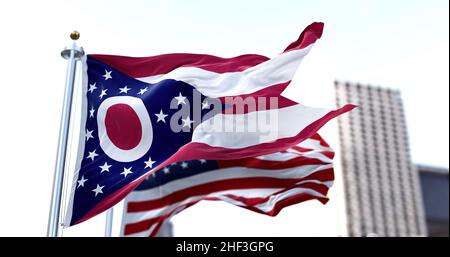the flag of the US state of Ohio waving in the wind with the American flag blurred in the background. Ohio state flag is the only non-rectangular flag Stock Photo