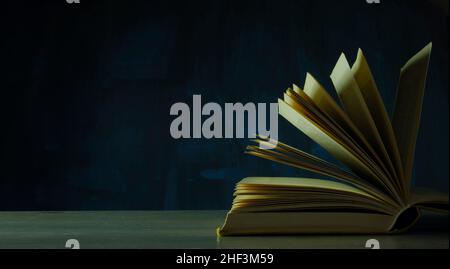Open book, hardback book on dark background. Back to school,education,reading. Copy space Stock Photo