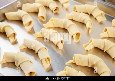 Close up of baking tray with raw crescent cookies on wooden table. Stock Photo
