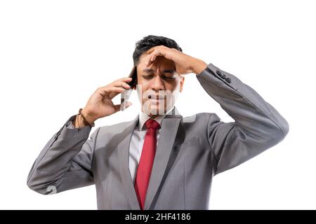 stressed young man wearing suit hold his head while making a phone Stock Photo