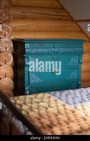 Ancient antique chest of drawers with carved ornaments renovated and painted turquoise located by wall, ready for eco-friendly re-use in wooden Stock Photo