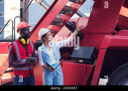 Foreman and woman engineer control loading Containers box from Cargo freight ship for import export. Freight containers in sea port. Stock Photo