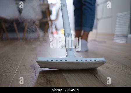 A steam mop washes the parquet on the floor of the house Stock Photo