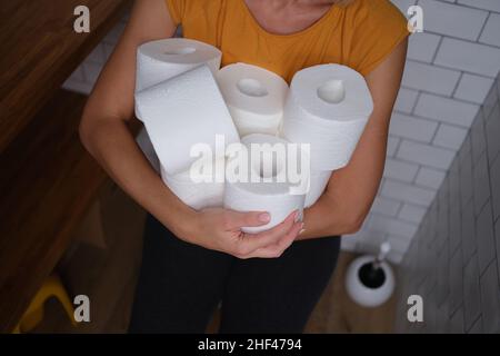 Woman in the wc holds many rolls of toilet paper Stock Photo
