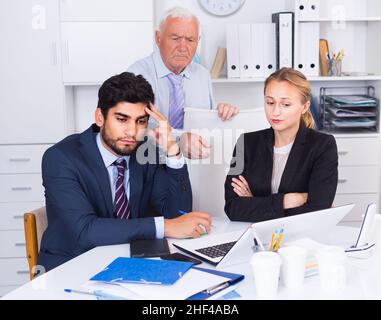 Mature boss is having complicated issue with reports made by subordinates Stock Photo
