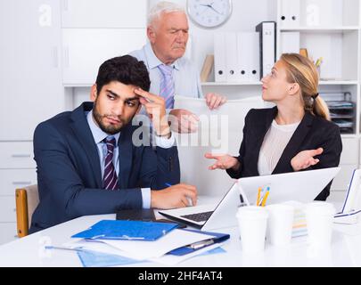 Mature boss is chastising employees because of uncompleted work Stock Photo