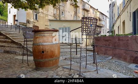 Outdoor seating of hip bar, bar stools around wooden barrel in scenic quarter of Corte, Corsica, France. Stock Photo