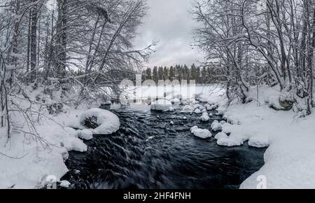 Flowing river in snowy winter landscape in Finland Stock Photo