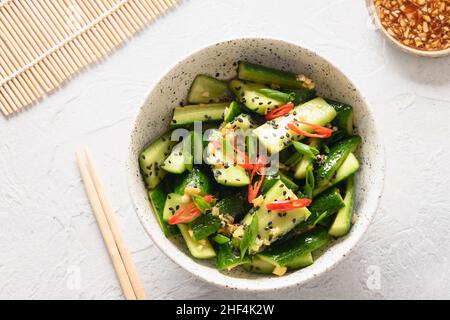 Asian spicy salad Broken Cucumbers with fresh coriander, ginger, pepper chili, black vinegar on white background. Popular Chinese cold appetizer. Top Stock Photo