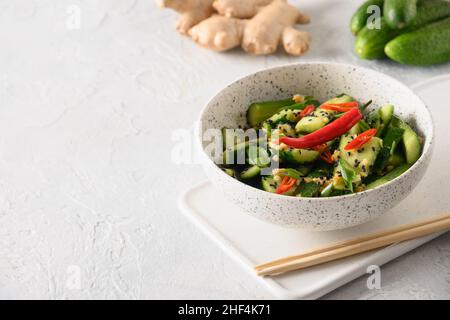 Asian spicy salad Broken Cucumbers with fresh coriander, ginger on white background. Popular Chinese cold appetizer. Close up. Stock Photo