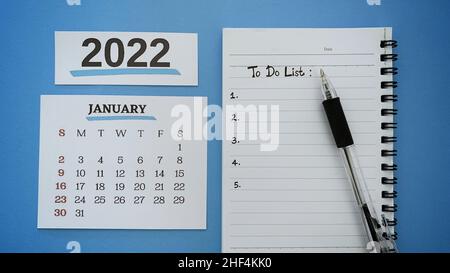 To do list text hand written on a notepad with month of January 2022 calendar and blue background. Stock Photo