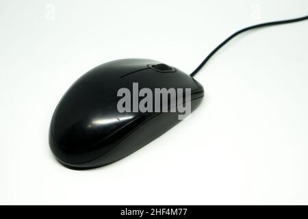 Black computer mouse uses a wired connection and uses an infrared sensor. White background. Stock Photo