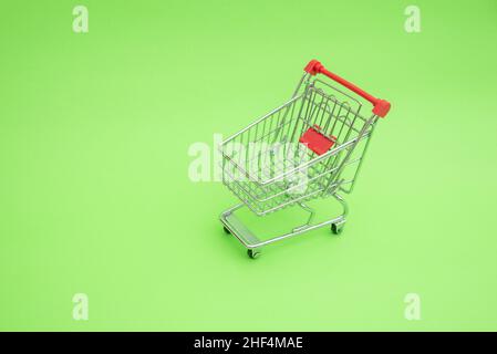 Empty shooping trolley cart on green background Stock Photo