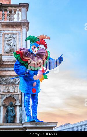Man in colourful arlecchino harlequin costume at the Campanile on St Mark's Square, Carnevale Di Venezia, Venice Carnival, Italy Stock Photo
