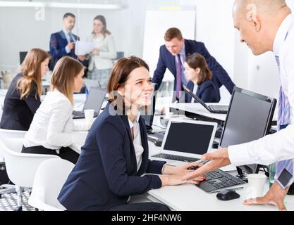 Friendly coworkers having pleasant fun conversation at workplace in modern office Stock Photo