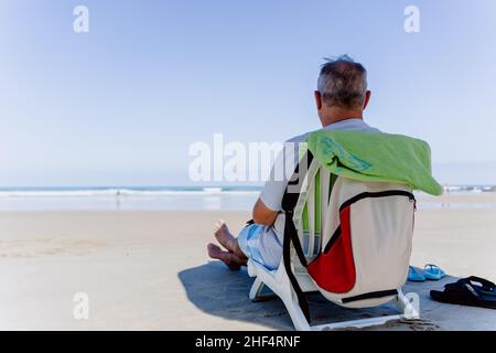 old man sitting on the beach Stock Photo