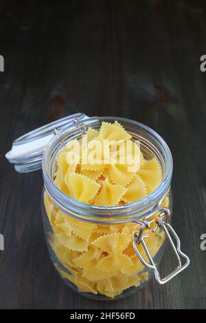 Uncooked Farfalle Pasta in a Glass Jar Isolated on Black Wooden Table Stock Photo