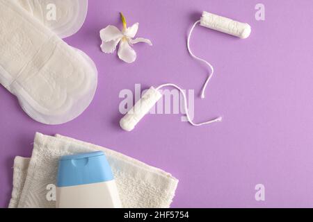 Various menstrual hygiene products, and intimate hygiene care.  Menstrual wipes and tampons intimate soap and towel on lilac. Top view. Stock Photo