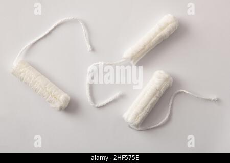 Three soft protective and absorbent cotton tampons for women's care on white background. Top view. Horizontal composition. Stock Photo