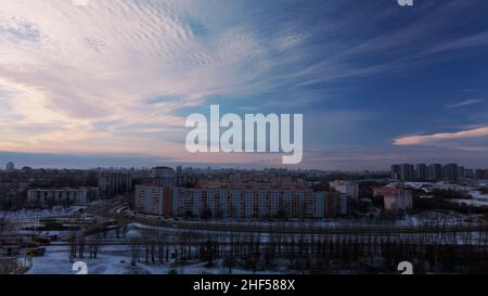 Flying over a snowy park. The city is visible on the horizon. Aerial photography. Stock Photo