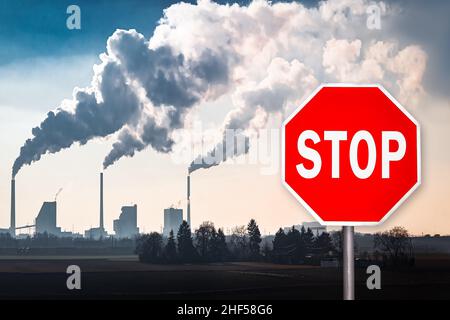Red Stop Sign in Front of the Smoke Stacks of a Coal Fired Power Plant Stock Photo