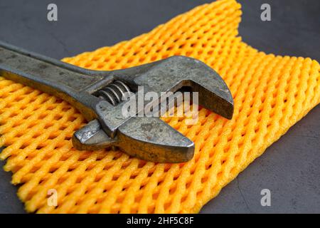 Old adjustable wrench for tightening nuts close-up on a yellow mat Stock Photo