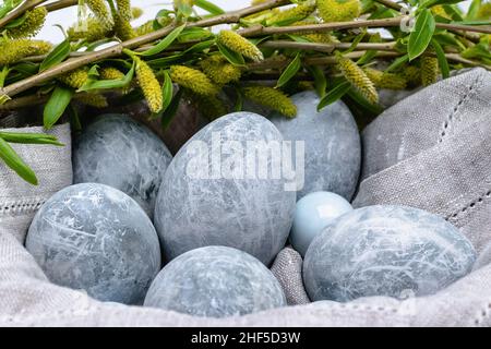 Close-up of marble-colored Easter eggs in a linen napkin and willow twigs. Horizontal photo. Stock Photo