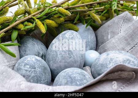 Easter background. Close-up of marble-colored Easter eggs in a linen napkin with willow sprigs. Horizontal photo. Stock Photo