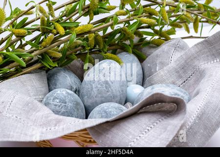 Marble-colored Easter eggs in a linen napkin with willow branches. Easter background. Horizontal photo. Stock Photo