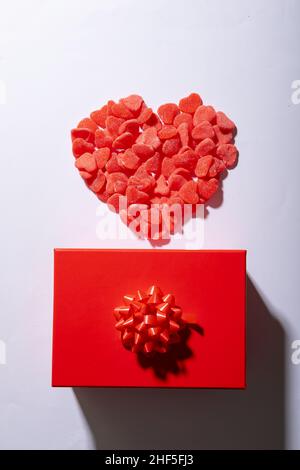 Overhead view of heart shaped red candies and gift box on white background, copy space Stock Photo