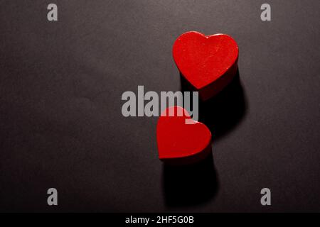 Overhead view of two red heart shapes with shadows by copy space on black background Stock Photo