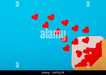 Open beige envelope with red heart shapes by copy space over blue background Stock Photo